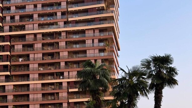 A hotel with a pool area, palm trees, and a multi-story building with balconies.