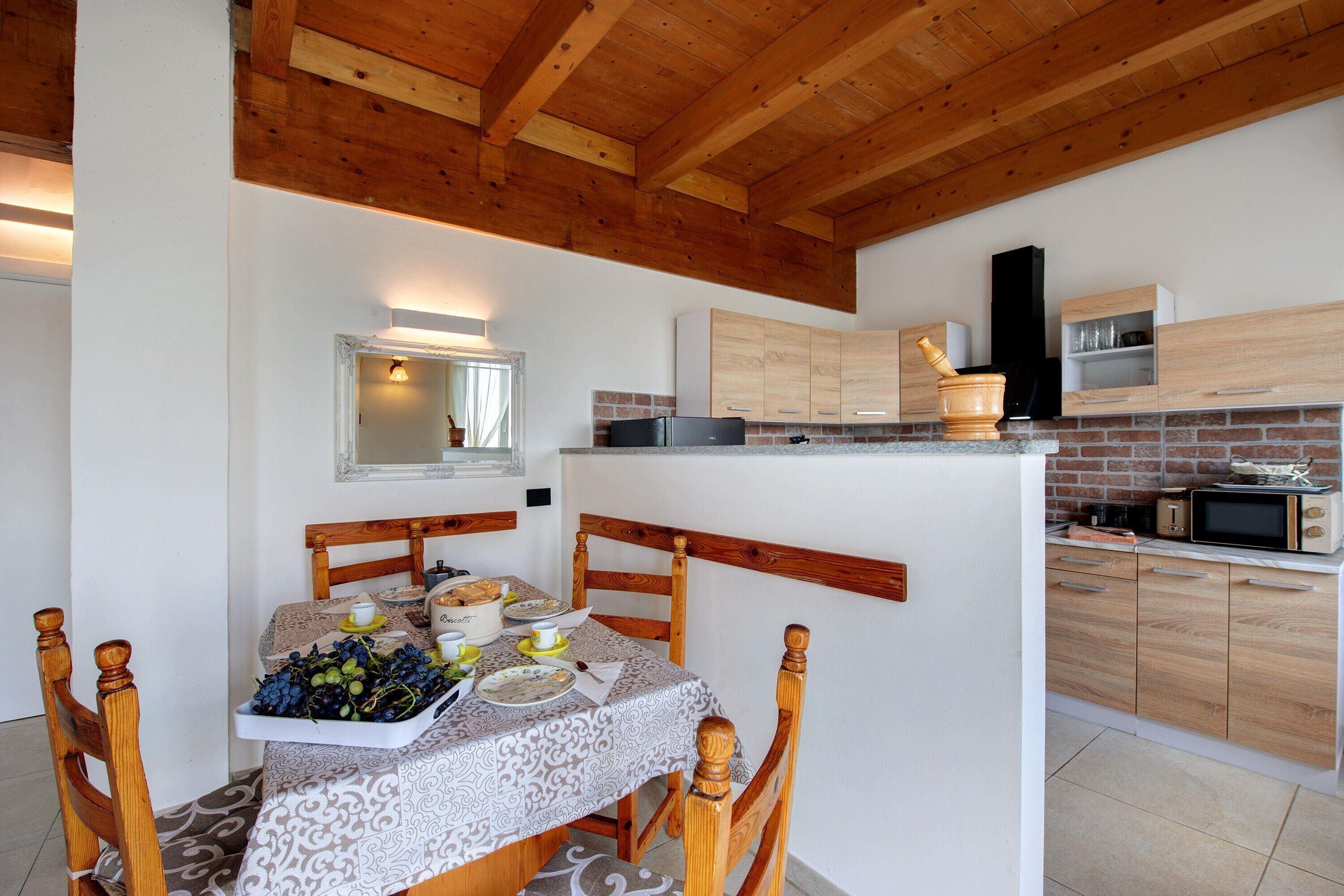 Una cocina con armarios de madera, una mesa de comedor con sillas y una pequeña isla con un microondas.