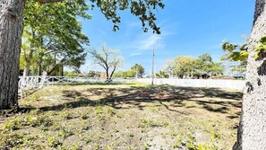 An outdoor area with trees, a fence, and a clear sky.