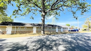 A row of motel buildings with a tree in the foreground. - #6 "The village" warm Studio (North Myrtle Beach)