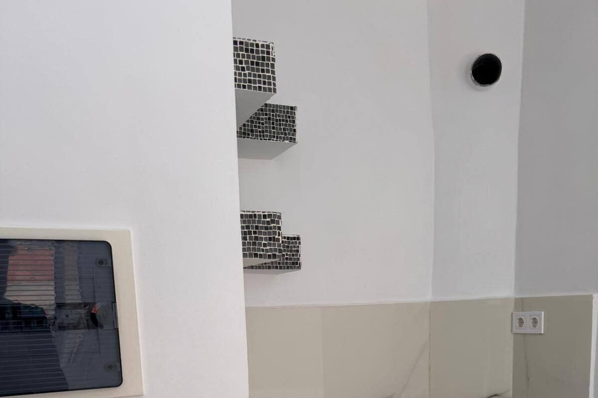 Una cocina moderna con encimera de mármol, pileta de acero inoxidable y muebles de cocina blancos.