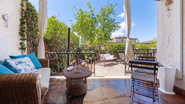 Un patio con mobiliario de mimbre, una mesa redonda y una zona de estar cubierta.