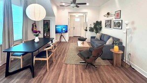 Un salon moderne comprenant un coin repas, un canapé, un téléviseur et un ventilateur de plafond.