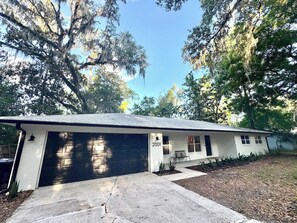 A single-story house with a garage, a small porch, and a number '2001' on the front wall. - Magnolia Modern, Near UF, Shands, Private (Gainesville)