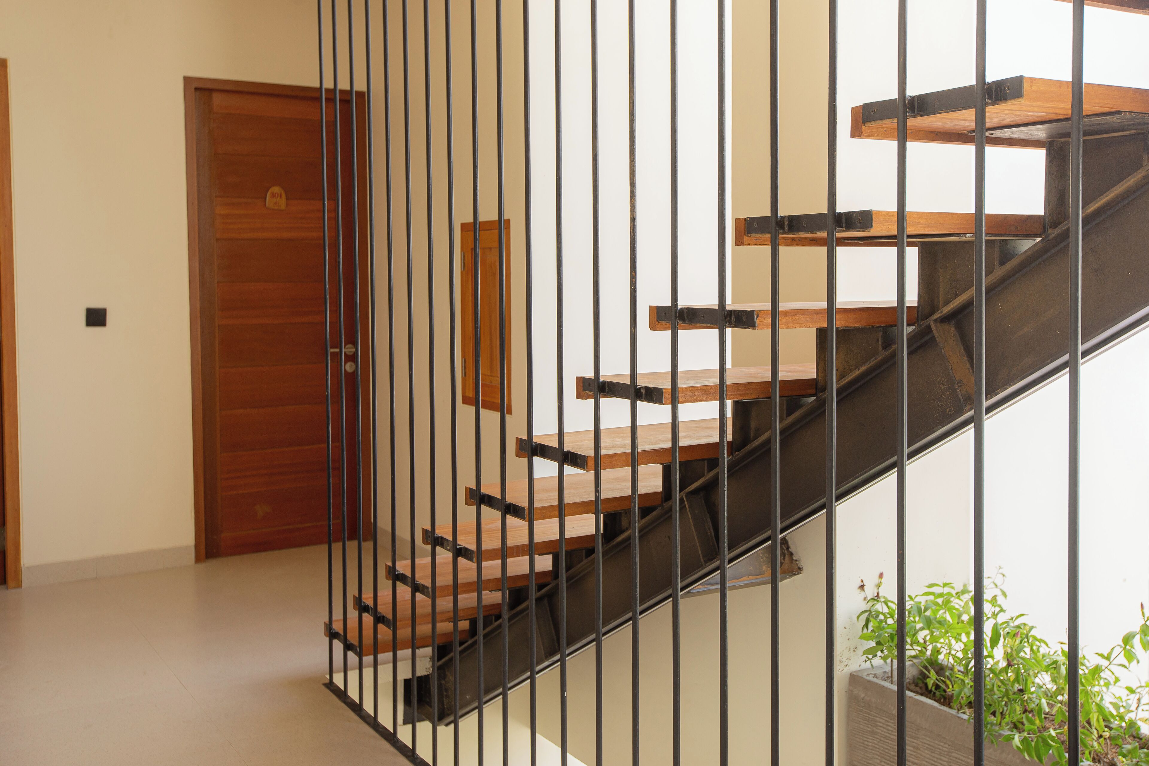 A staircase with wooden steps and metal railings, leading to a wooden door.