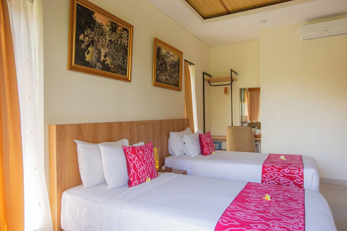 A hotel room with two beds, a wooden headboard, and two framed artworks on the wall.
