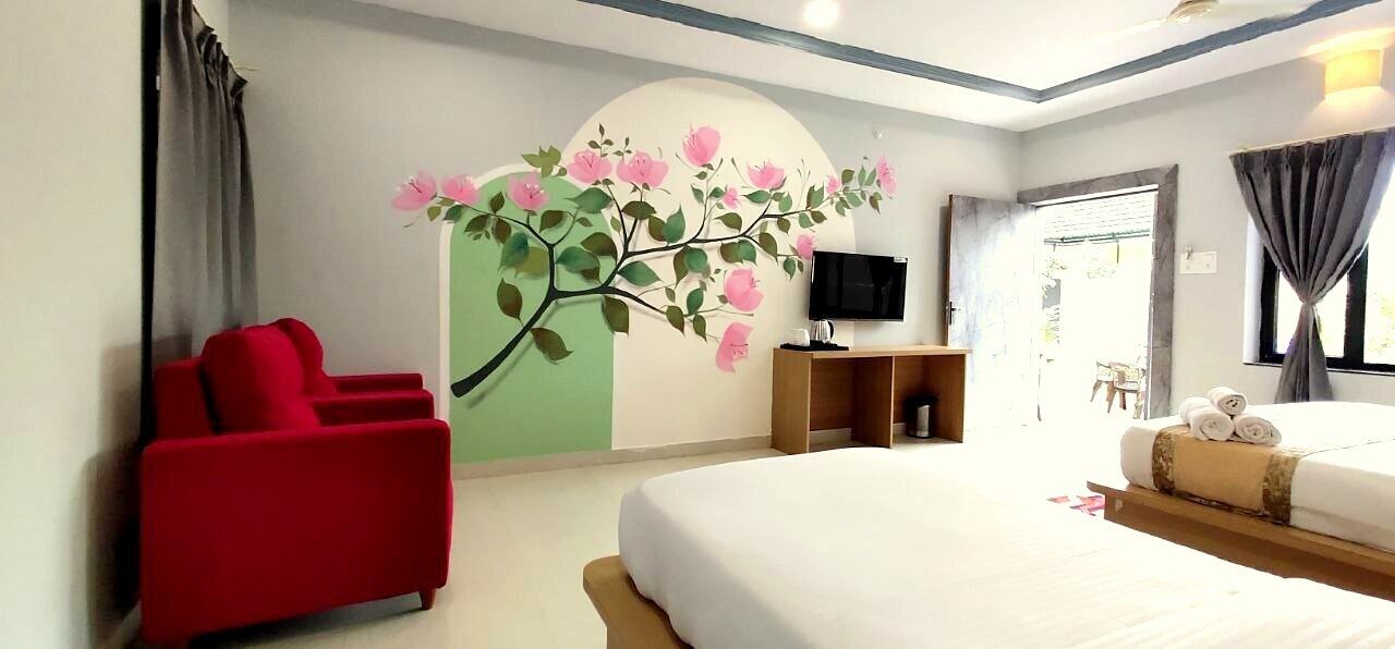 Une chambre d’hôtel avec un grand lit, un fauteuil rouge, une télévision et une fresque murale.