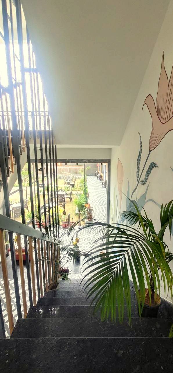 Eine Treppe mit Metallgeländer führt zu einem Außenbereich mit Blumentöpfen und Blick auf einen Garten.