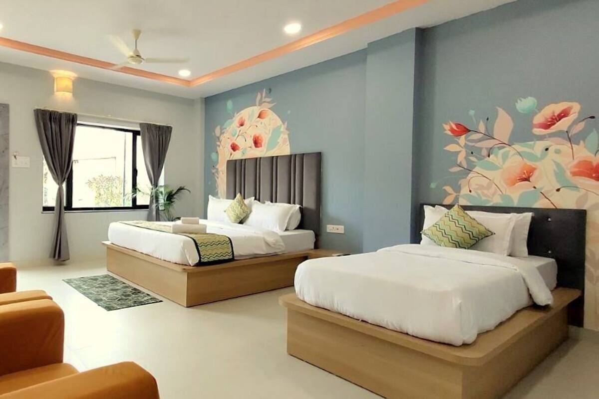 A hotel room with two beds, a sofa, a TV, and a window with curtains.