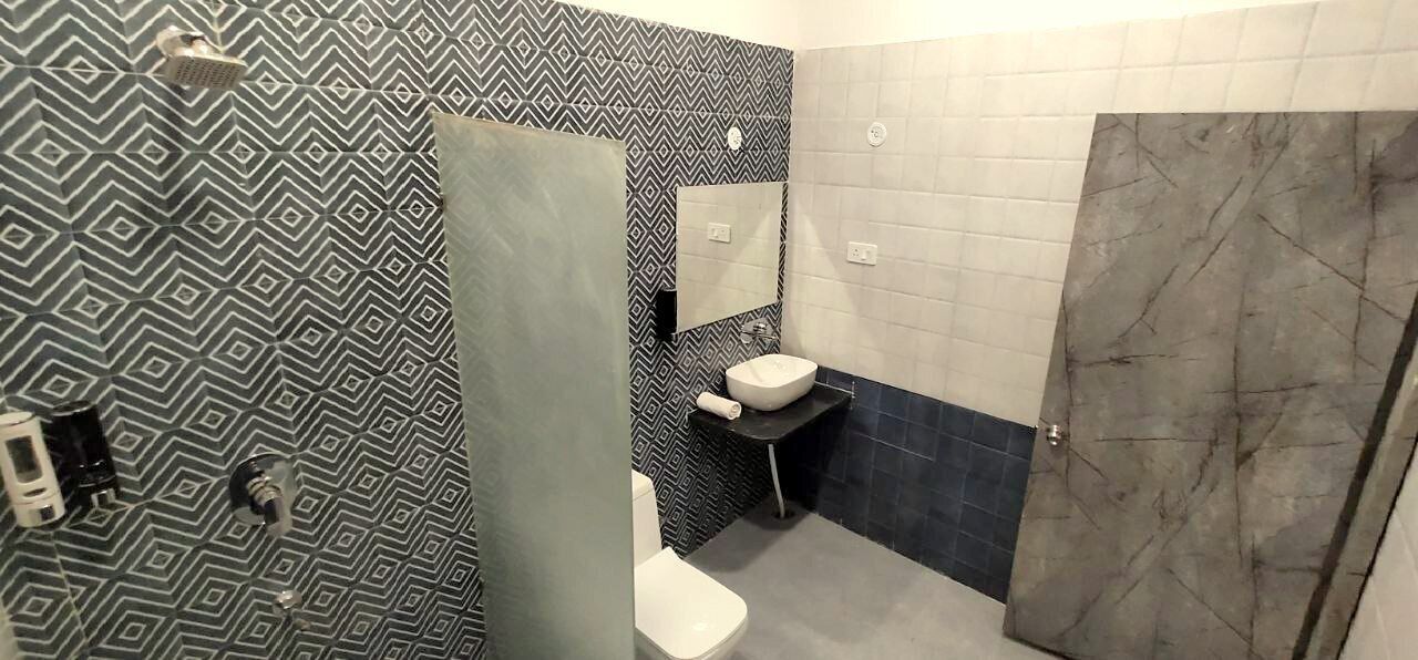 A bathroom with a patterned wall, a white sink, and a shower area.