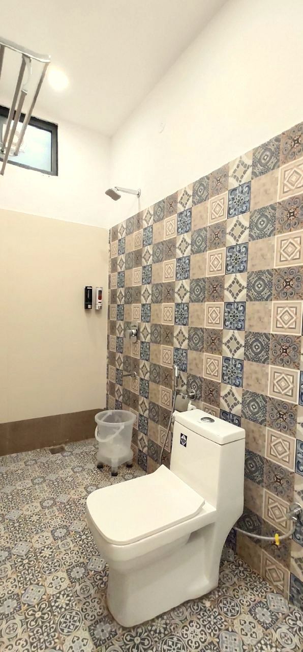 A bathroom with a toilet, a shower, and patterned tiles on the walls and floor.