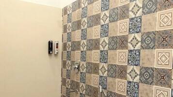 A bathroom with a toilet, a shower, and patterned tiles on the walls and floor.