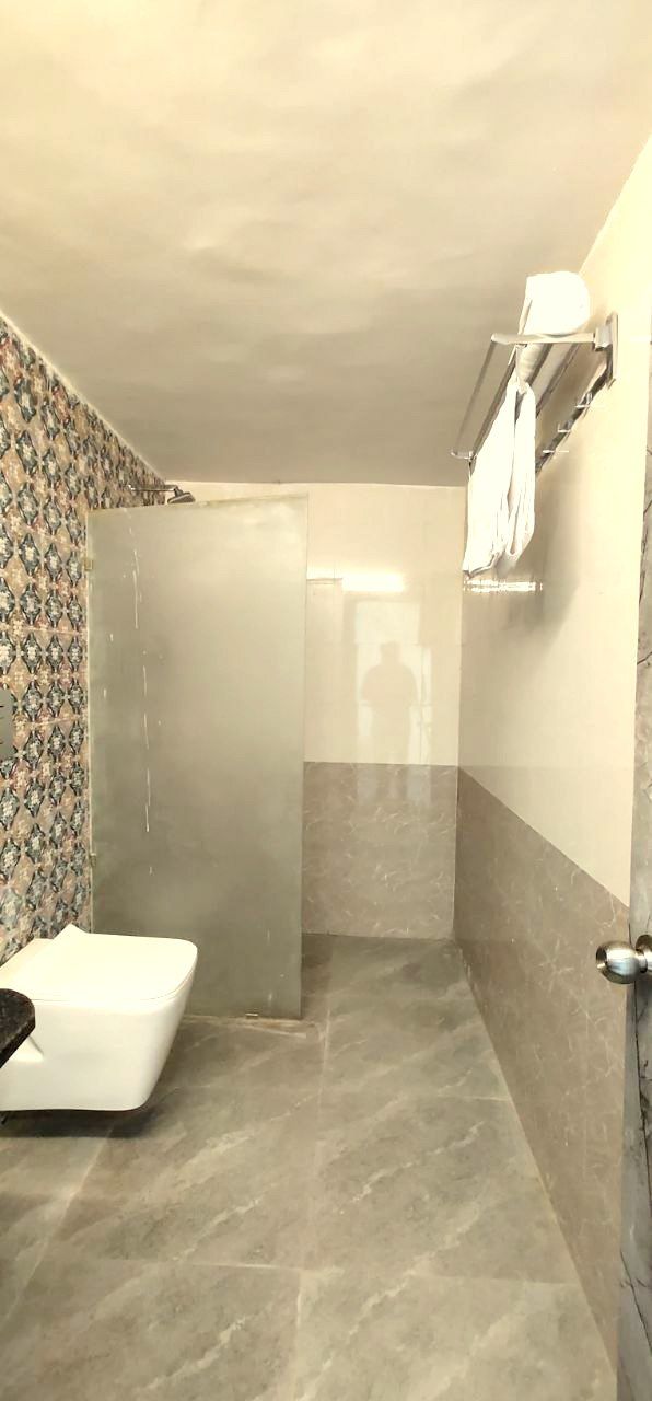 Un baño con ducha, inodoro y perchero para toallas.