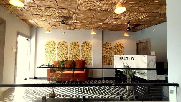 Un área de recepción con diseño moderno, que incluye un mostrador de recepción, un espacio de espera con sofá y sillones, y paneles decorativos en la pared.