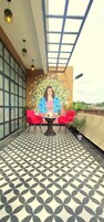 Un balcón con suelo estampado, dos sillas rojas, una mesa y un mural de una mujer.