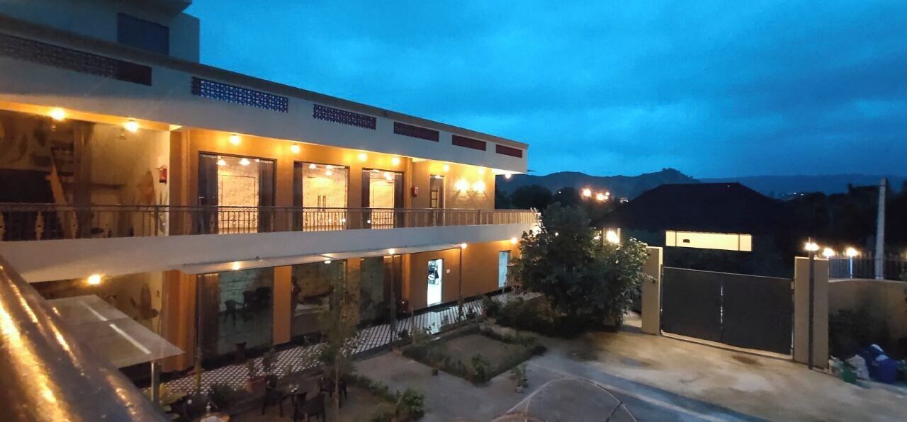A hotel with multiple balconies, a covered outdoor seating area, and a view of the surrounding landscape.