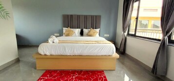 Una camera da letto con un letto grande, una pedana in legno e un tappeto rosso decorato.