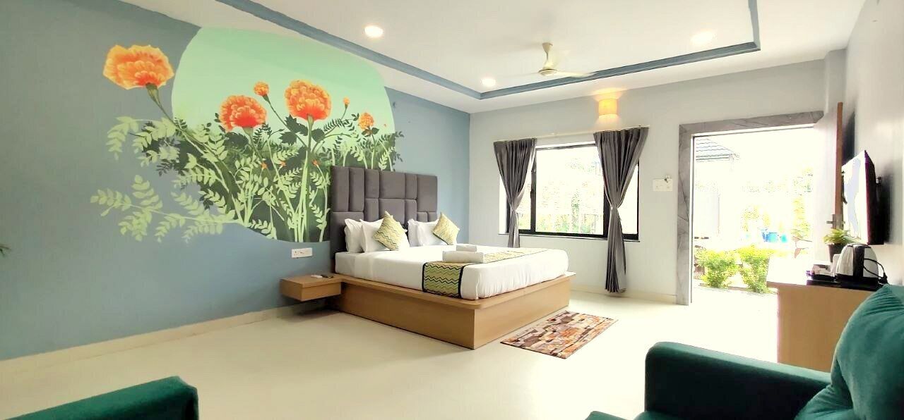 A modern bedroom with a bed, a nightstand, a wall mural, a window with curtains, and a television on the wall.