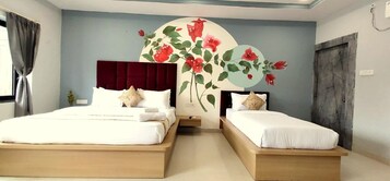 Un dormitorio con dos camas, un amplio mural floral en la pared y una puerta de madera oscura.