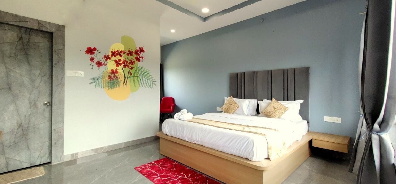 A modern bedroom with a large bed, a red chair, and a wall mural.