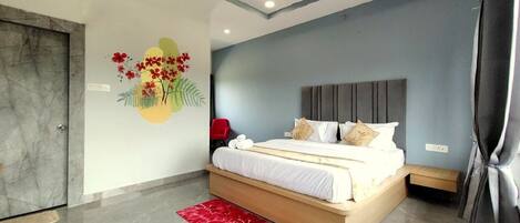 A modern bedroom with a large bed, a red chair, and a wall mural.