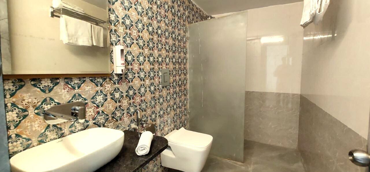 A bathroom with a double sink, toilet, and a glass-enclosed shower.