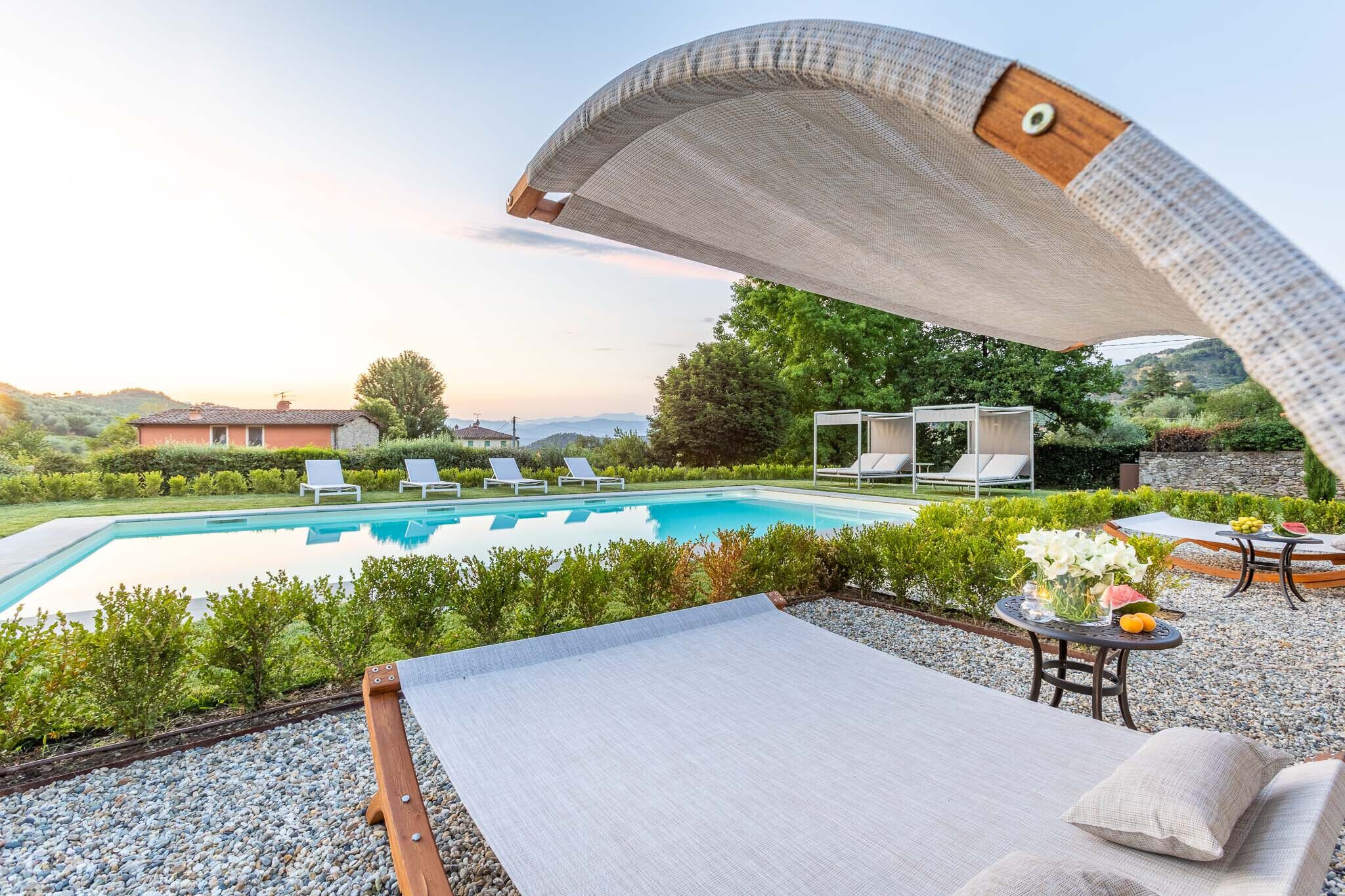 Un espace aménagé au bord de la piscine, avec des chaises longues, un coin salon abrité et une vue sur le paysage environnant.