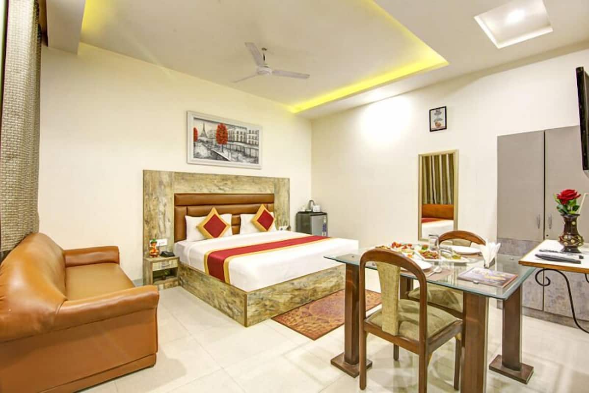 Une chambre d’hôtel comprenant un lit, un canapé en cuir, une table à manger avec des chaises, un ventilateur de plafond et un tableau accroché au mur.
