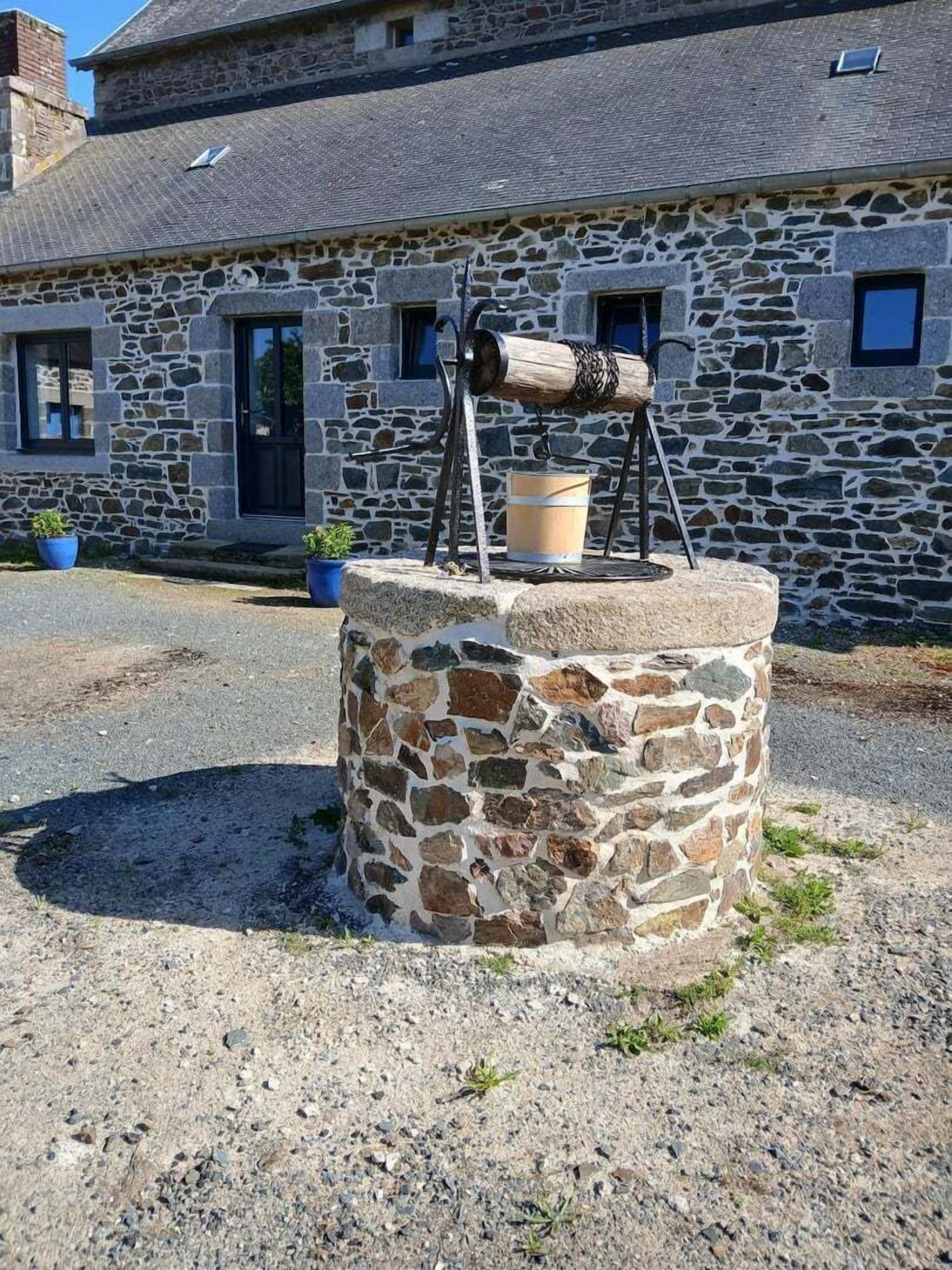 A stone building with a traditional stone well and a wooden barrel on top.