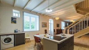 A modern kitchen with a central island, a built-in washing machine, and a dining area with chairs. - Charming cottage in the countryside (6 bedrooms) (Saint-Clet)