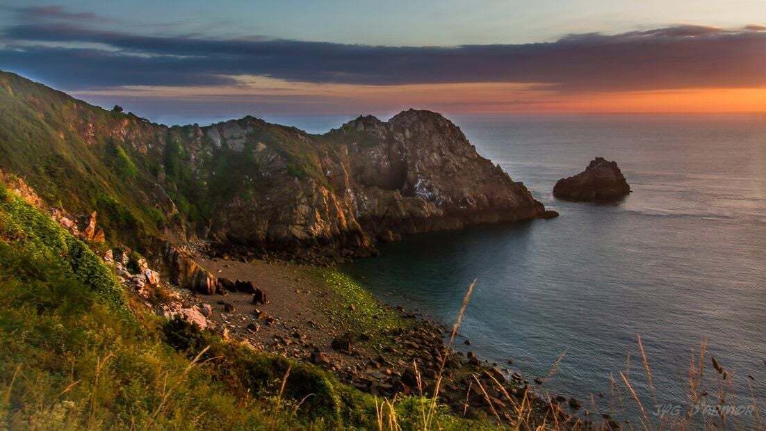 A coastal landscape with rocky cliffs and a calm sea.