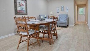 Un comedor con una mesa y sillas de madera, una lámpara y cuadros en la pared.