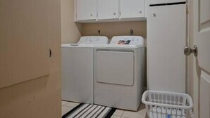 Un lavadero con lavadora, secadora y una cesta de ropa.