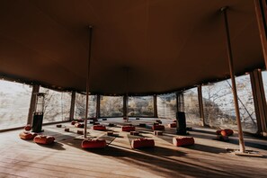 A spacious room with a high ceiling, large windows, and a wooden floor.