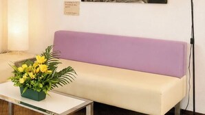 Ein Zimmer mit einem violetten Sofa, einem kleinen Tisch mit Blumenarrangements und einem an der Wand befestigten Schild.