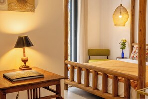 A wooden bed with a headboard, a bedside table with a lamp, and a book.