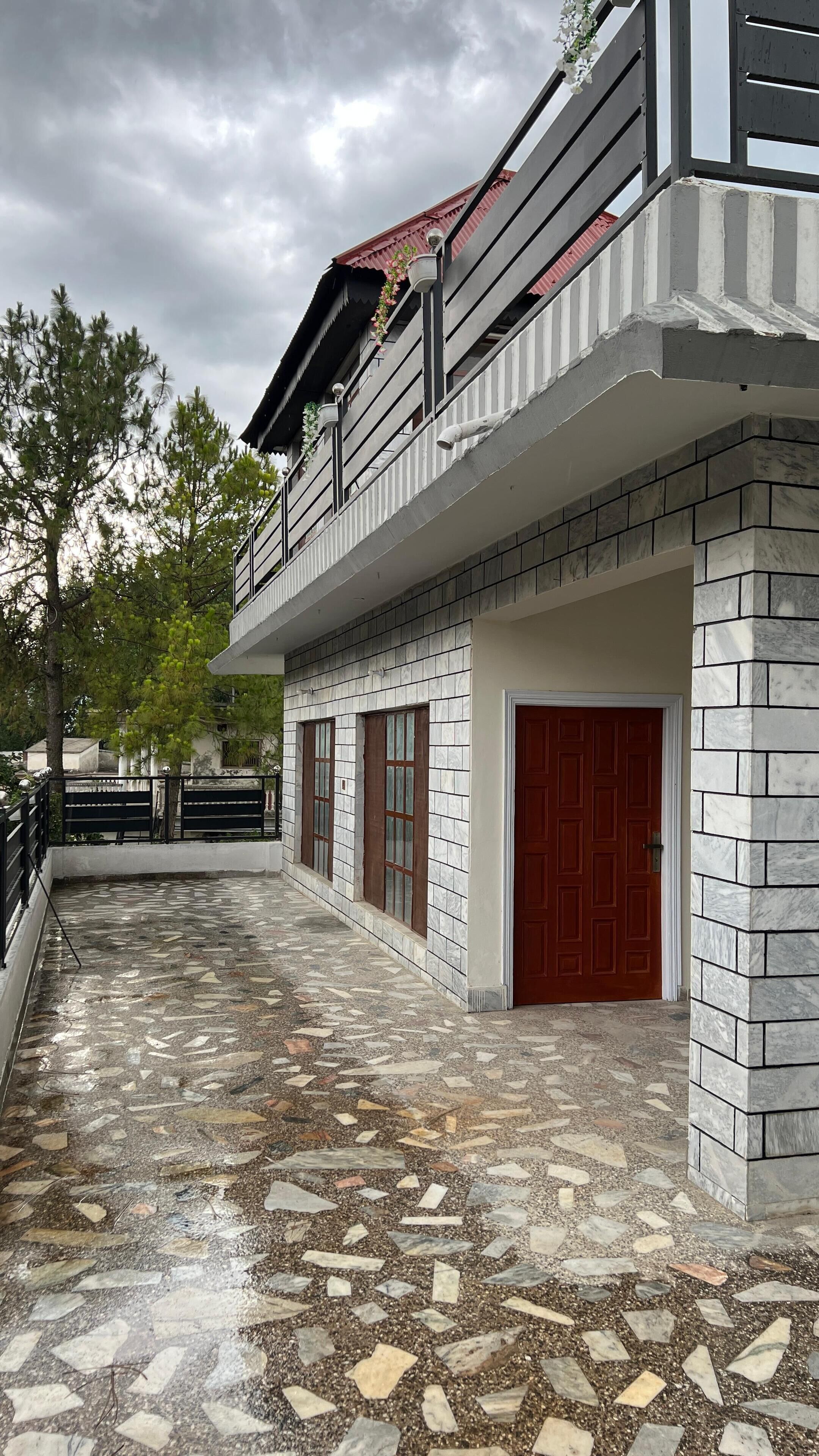 A building with a tiled exterior, a red door, and a balcony with railings.