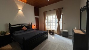 Un dormitorio con cama, lámpara de noche, ventana con cortinas y cómoda.
