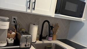 A modern kitchen with white cabinets, a built-in microwave, a toaster, and a coffee maker. - Charming 1-bedroom, 1st Floor Condo in North Wildwood. 2 Blocks to Beach! (North Wildwood)