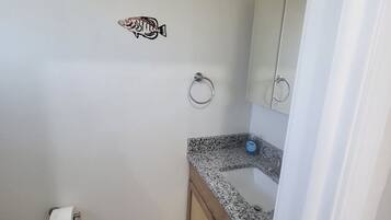A bathroom with a toilet, sink, and mirror. There are two fish decals on the wall.