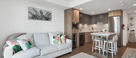 Una cocina moderna con una isla central, electrodomésticos integrados y un comedor con taburetes de bar.