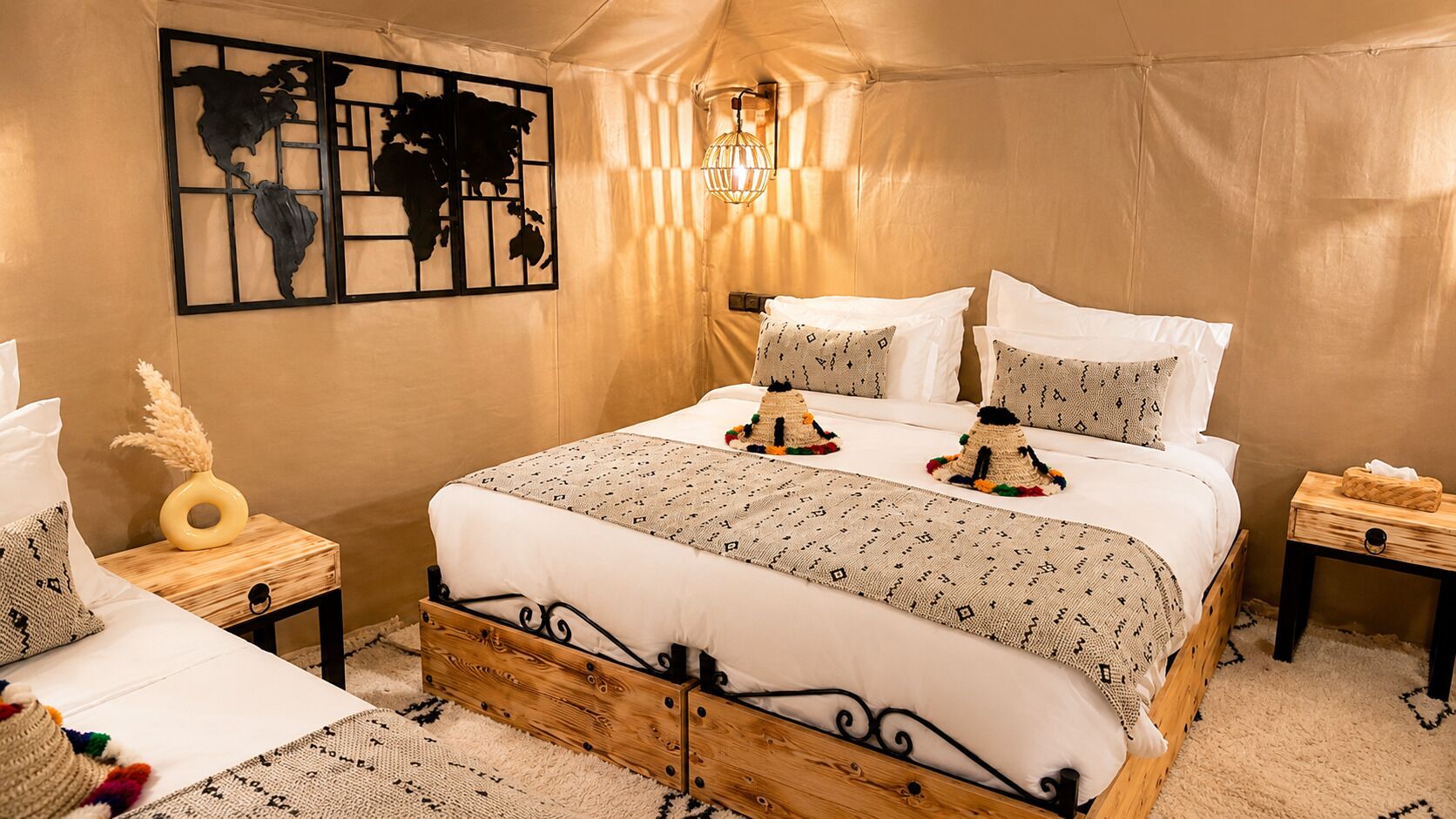 A tented room with a bed, a wall art piece, a lamp, and a small wooden nightstand.