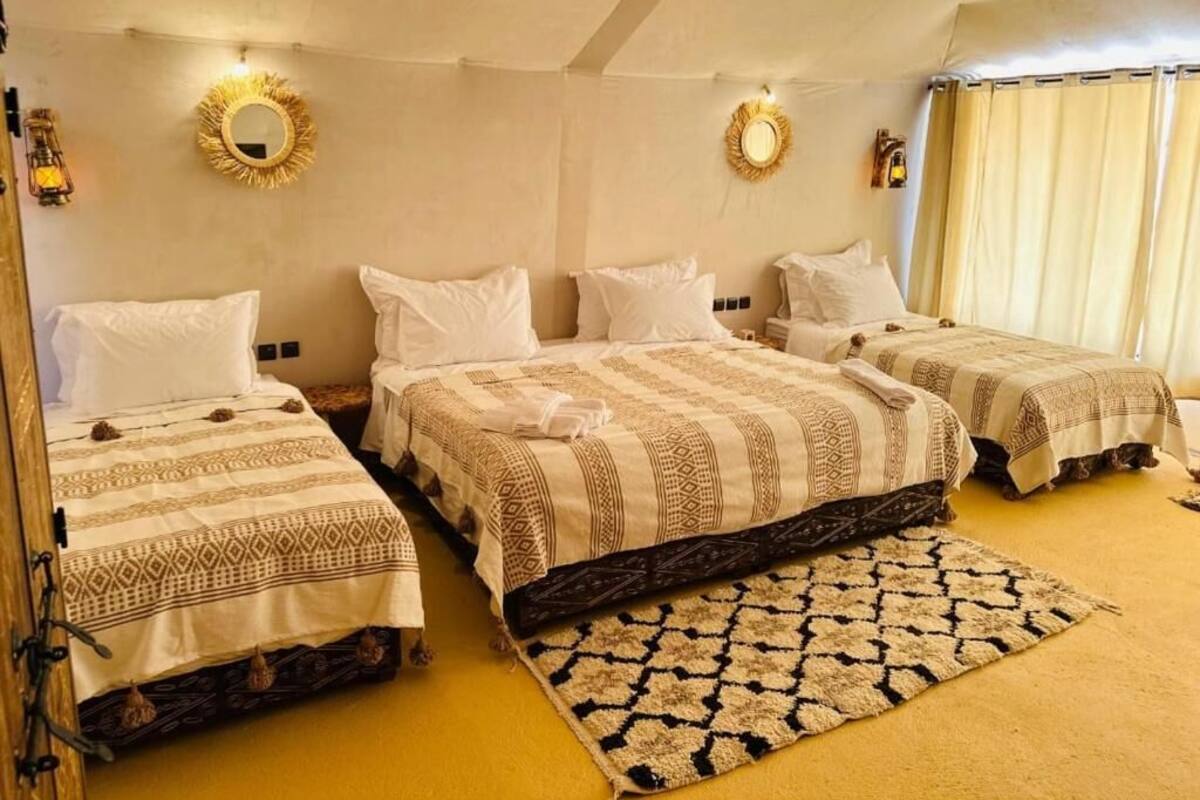 A room with three beds, each with patterned bedding and a central rug.