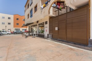 A building with a closed front door, a visible window, and a balcony with hanging laundry.