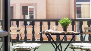 A balcony with a table, chairs, a potted plant, and a window.