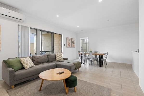 A modern living room with a sofa, a round coffee table, and a dining area with a table and chairs.