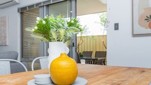 Una mesa de madera con un jarrón blanco que contiene follaje verde y un jarrón amarillo.
