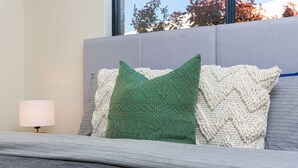 A bed with a grey headboard, a green pillow, and a white knitted throw. - Family perfection in quiet & convenient location! (Balcatta)