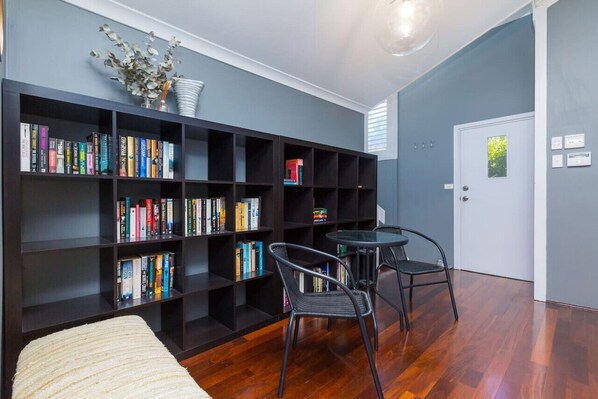 A room with a bookshelf, two chairs, a small table, and a door.