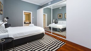 A modern bedroom with a large bed, a mirror, and a skylight.